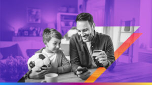 person smiling looking down at phone with card in hand next to a child holding soccer ball also looking at phone smiling