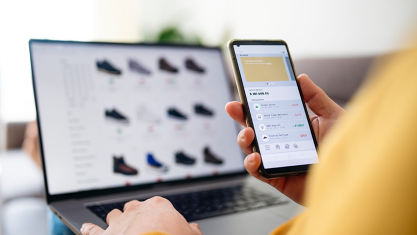 person using a phone and laptop to shop online